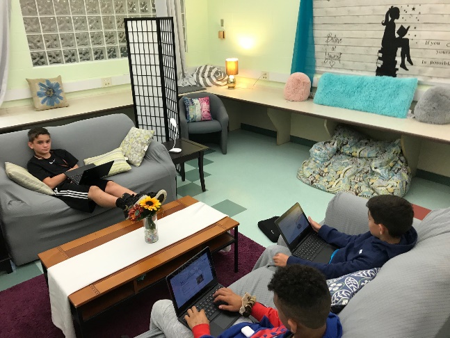 Three students sitting on couches and working on laptops