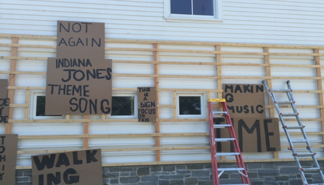 A wall with a wooden frame in front of it and a few cardboard signs attached to it