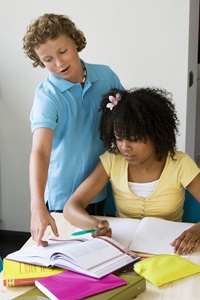 two students looking at a textbook, boy is pointing to a section of the book