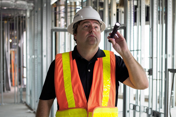 An individual holding a flashlight with his left hand is inspecting a construction in progress