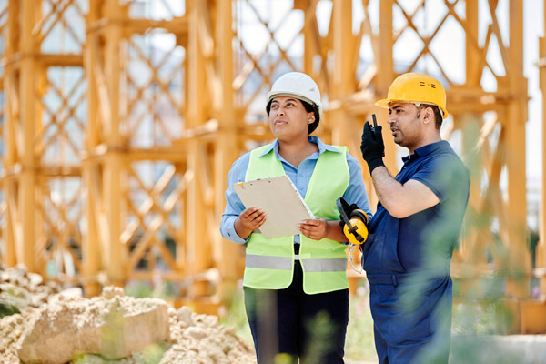 A woman and a man wearing security clothes doing a construction inspection