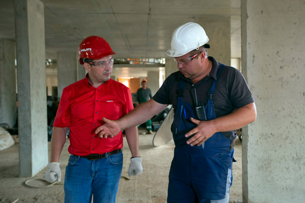 Two construction workers discussing details in a construction in progress