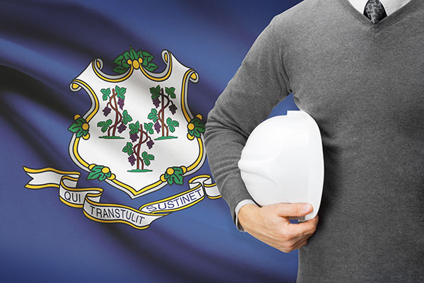 man holding hardhat in front of CT flag