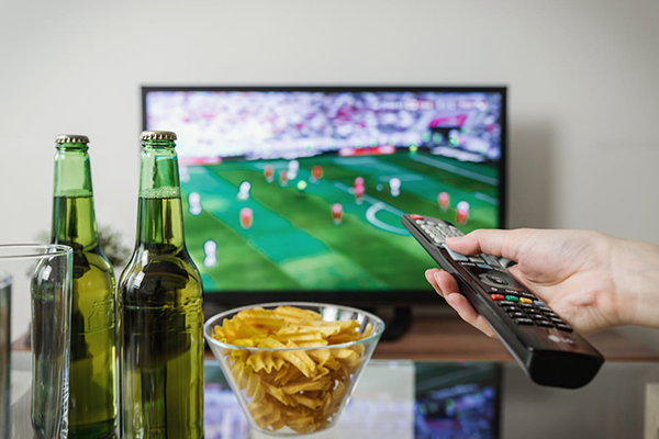 superbowl scene with person holding remote.