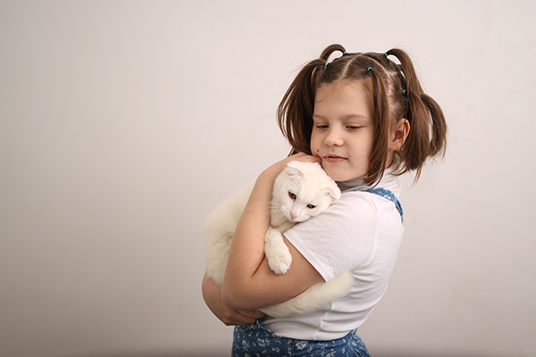 A young girl holding a cat.