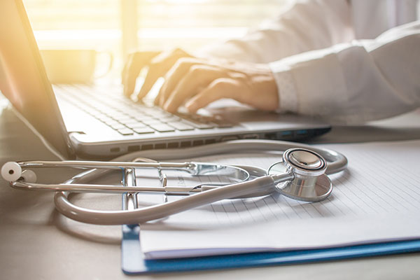 person on computer with stethoscope