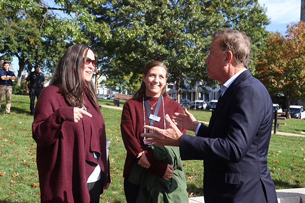 Governor Lamont speaking with two college graduates.