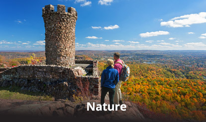 people at the top of a hill overlooking fall foliage