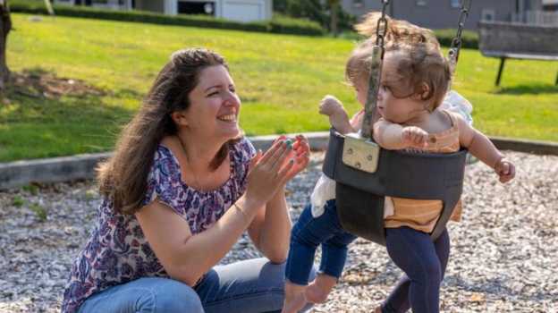 Woman playing with children on swings 