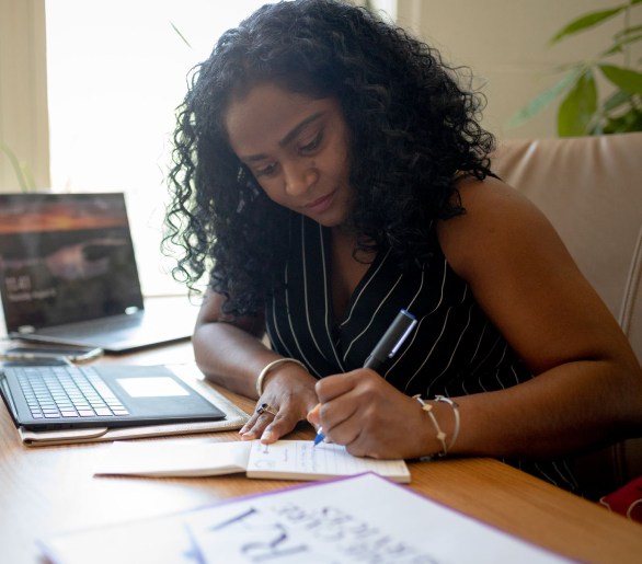 Woman at a desk writing in notebook